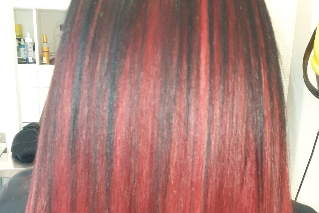 Achteraanzicht van lang steil haar in diep rood met zwarte banen, gekleurd en gestyled in de salon